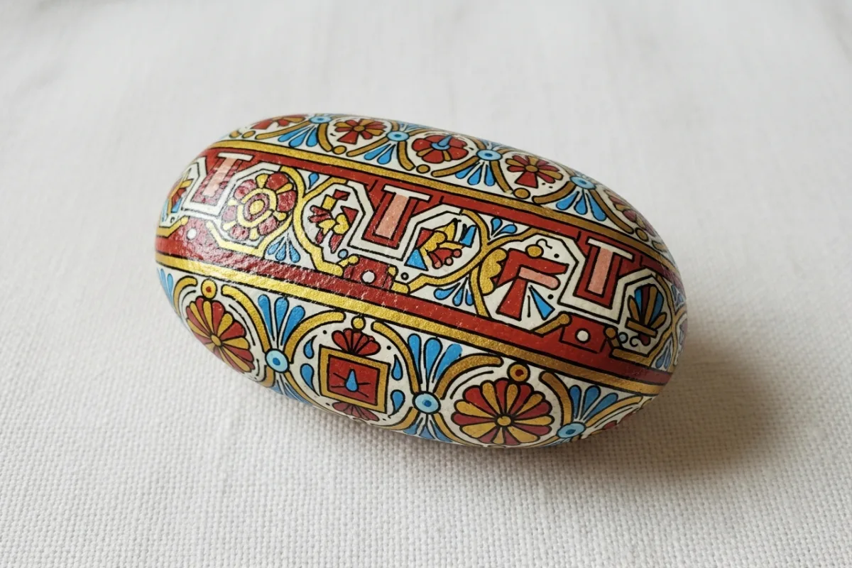 Smooth stone with Sicilian folk art motifs in terracotta, gold and azure blue